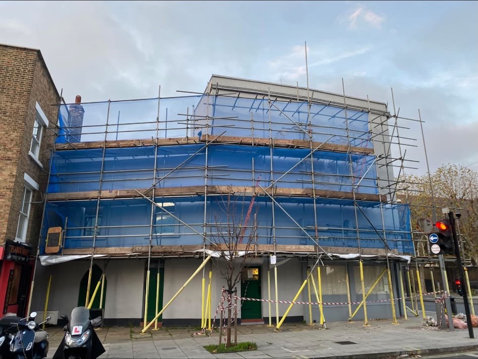 Scaffolding with blue netting around a corner building